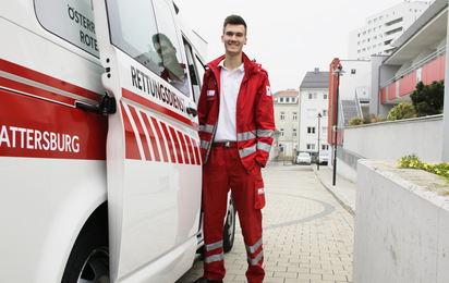 Zivildiener unterstützen das Rote Kreuz: so auch Manuel, der gerade in Uniform bereit zum Dienst neben dem Rettungswagen steht.